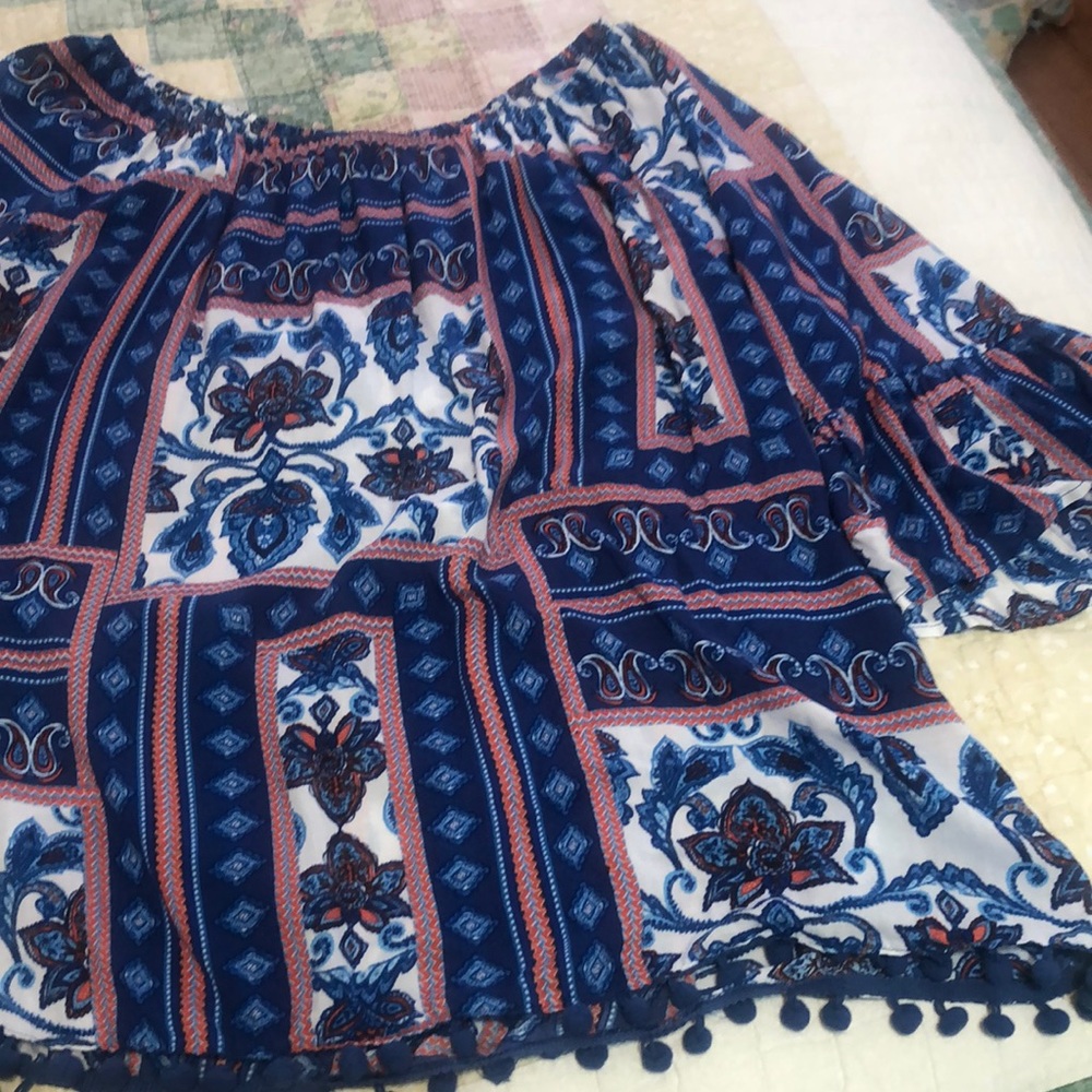 Cato top on blue, white and orange with blue Pom poms and bell sleeves.